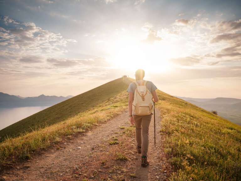 Young man travels alone walking on trail and enjoying on view of mountains and sea landscape at sunset , the lifestyle concept of traveling outdoors.