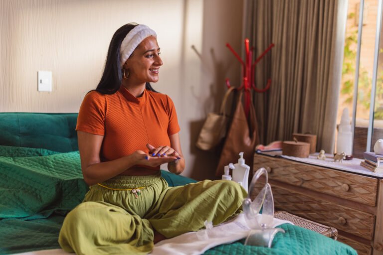 Linda mulher indigena sentada na cama fazendo sua rotina de cuidados com a pele.